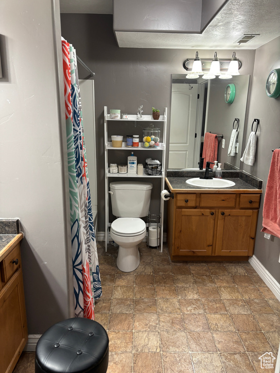 Bathroom featuring toilet, stone finish flooring, vanity, baseboards, and a shower with curtain