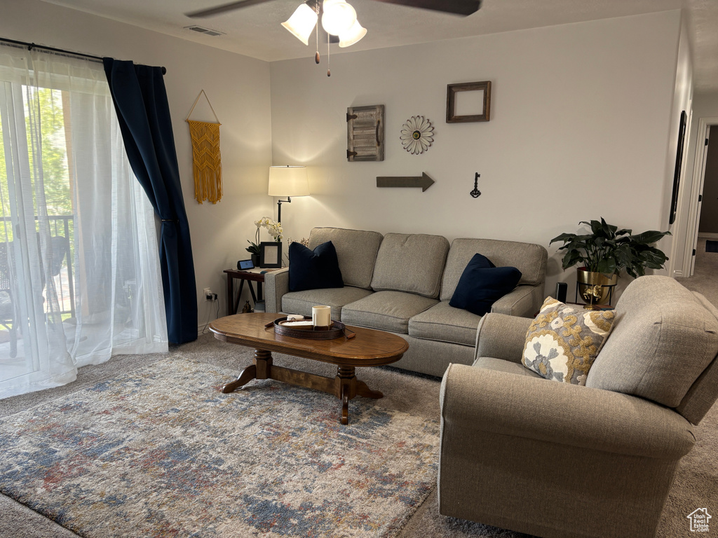 Carpeted living room with a ceiling fan