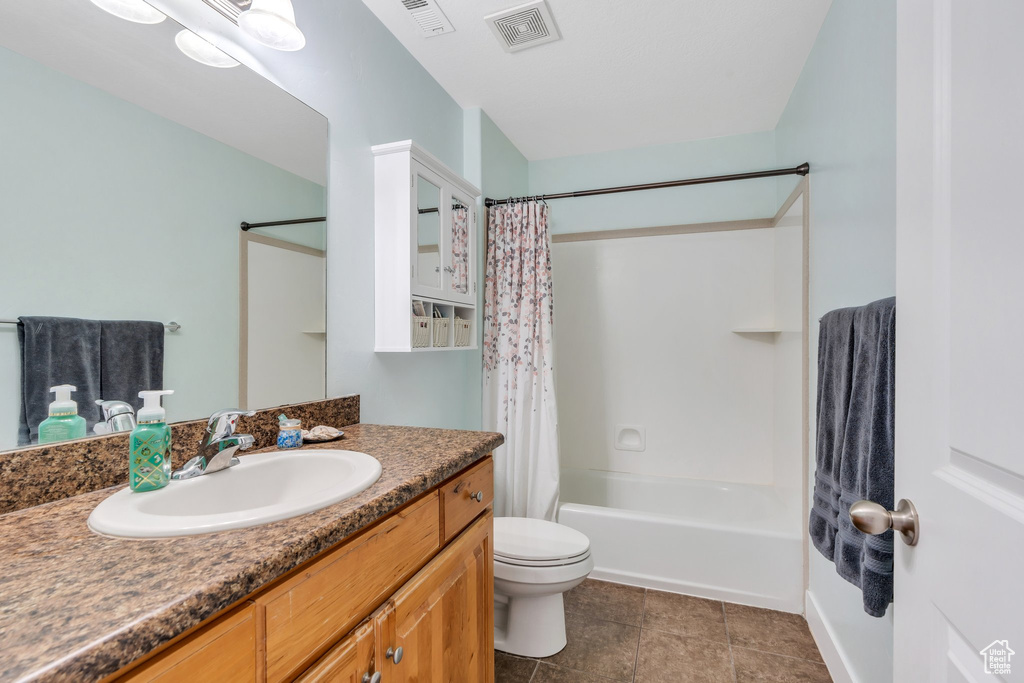 Full bathroom with toilet, vanity, shower / bath combo with shower curtain, and tile patterned flooring