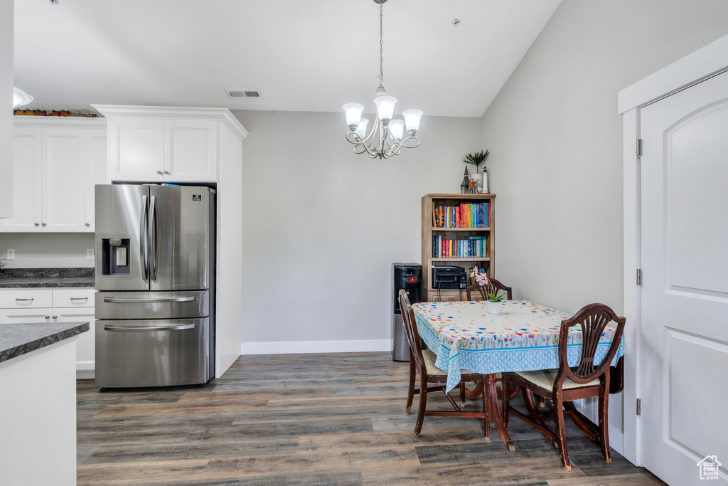 Dining space with a chandelier, dark wood-style floors, baseboards, and lofted ceiling