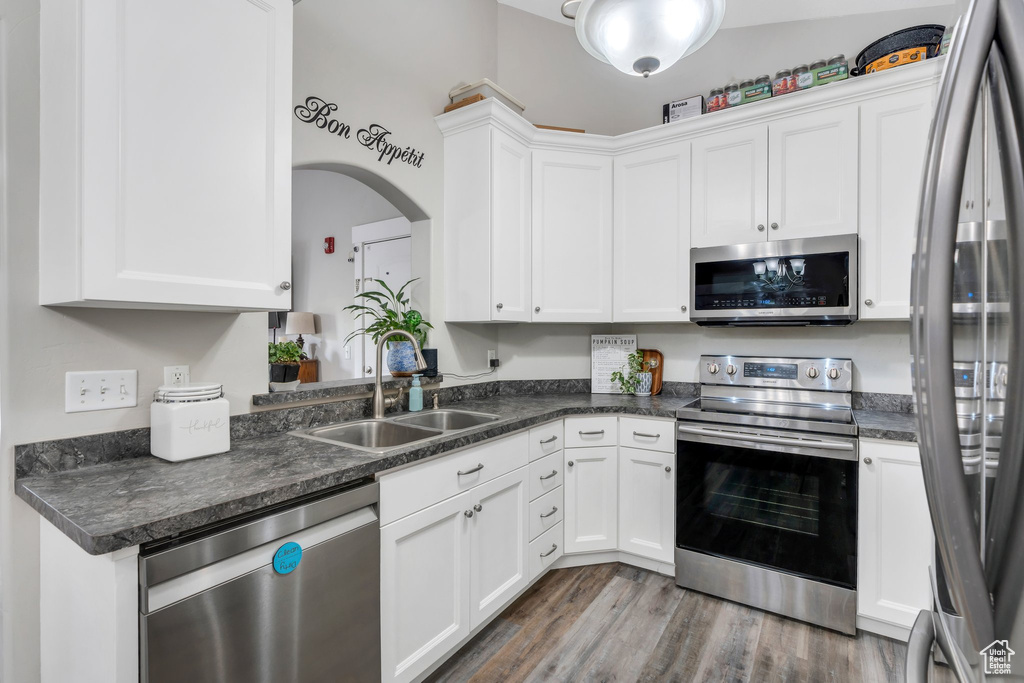 Kitchen featuring stainless steel appliances, a sink, white cabinetry, and dark wood-style floors