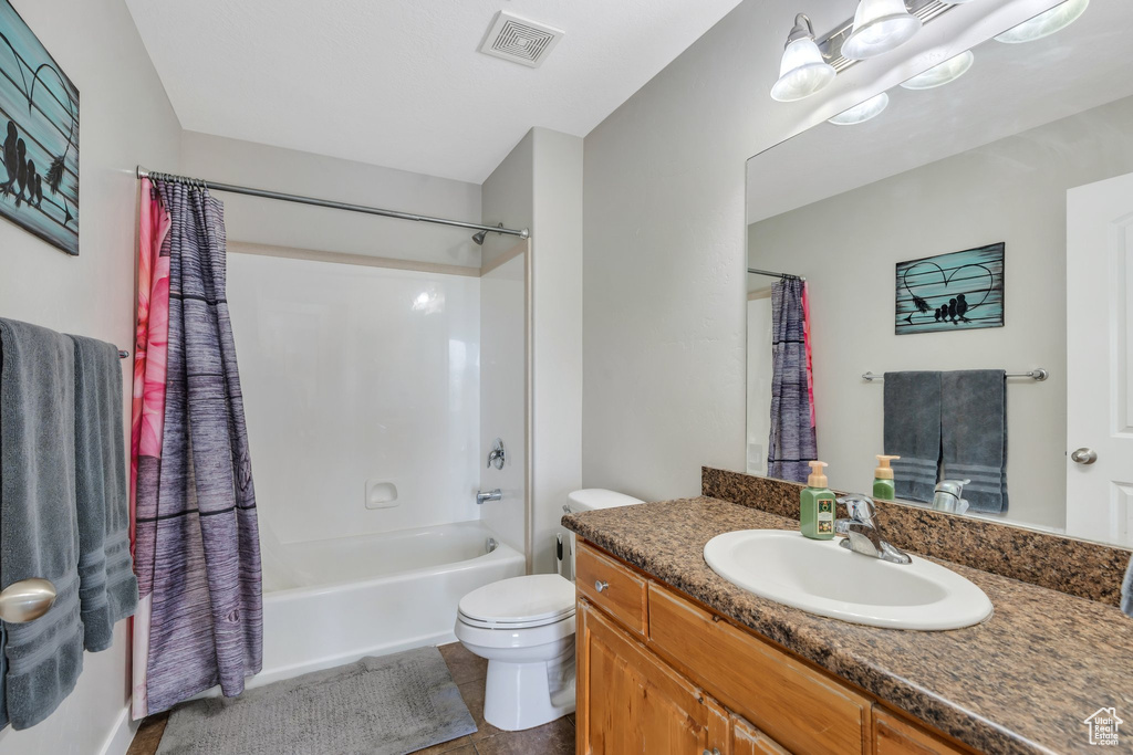 Bathroom featuring toilet, vanity, and shower / bath combo with shower curtain