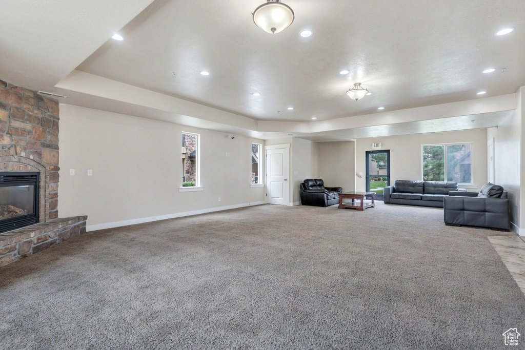 Living room with carpet, recessed lighting, baseboards, a fireplace, and a tray ceiling