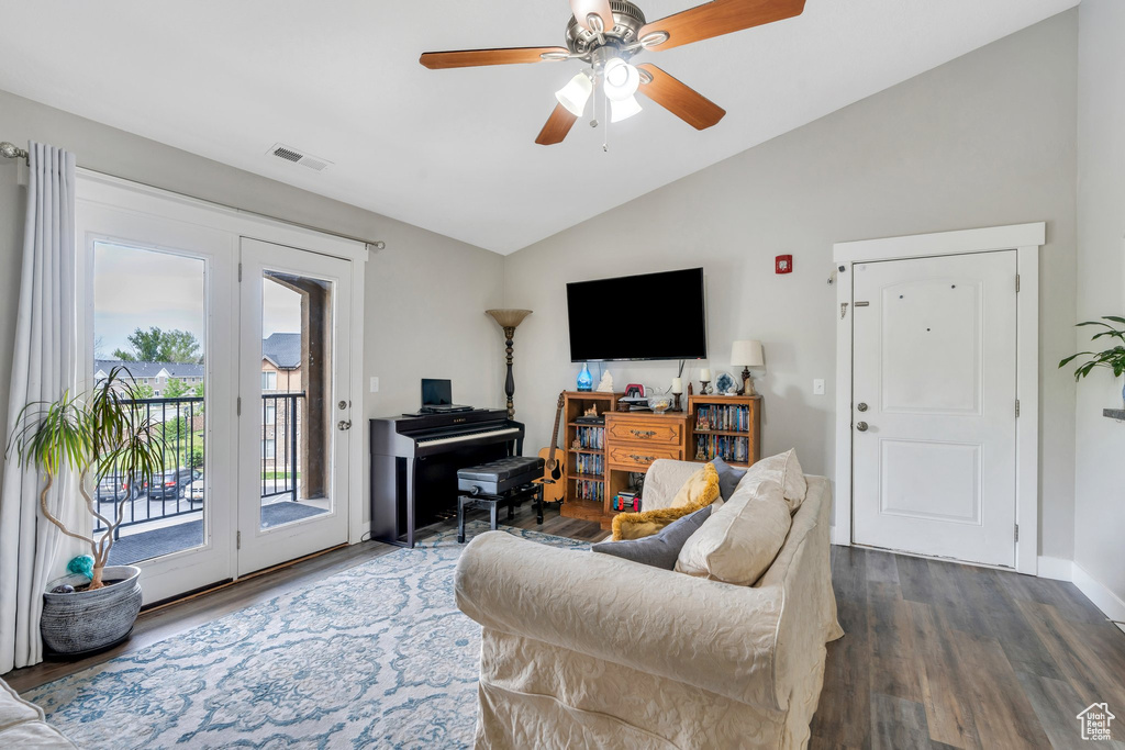 Living area with vaulted ceiling, dark wood-style floors, ceiling fan, and baseboards