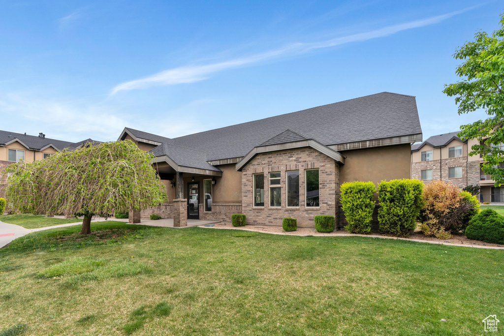 View of front of home with a front yard, brick siding, and a shingled roof