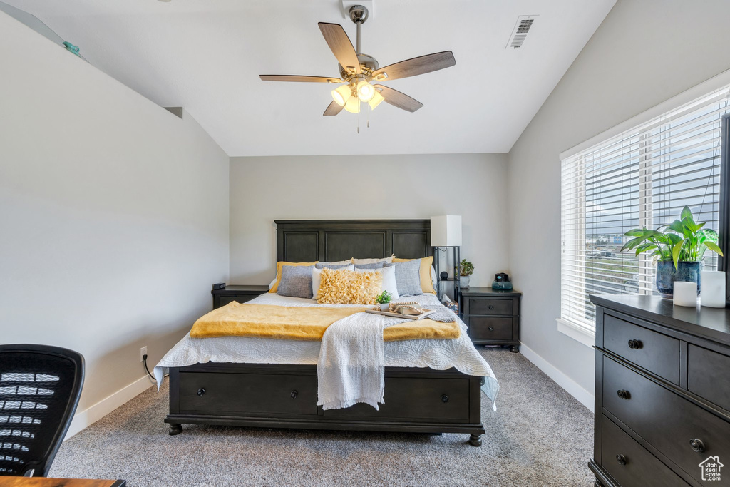 Bedroom with vaulted ceiling, baseboards, light colored carpet, and a ceiling fan
