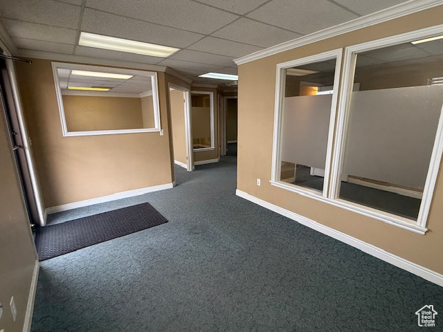 Hall featuring dark carpet, baseboards, a paneled ceiling, and ornamental molding