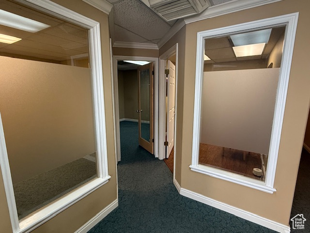 Hallway featuring dark colored carpet and baseboards