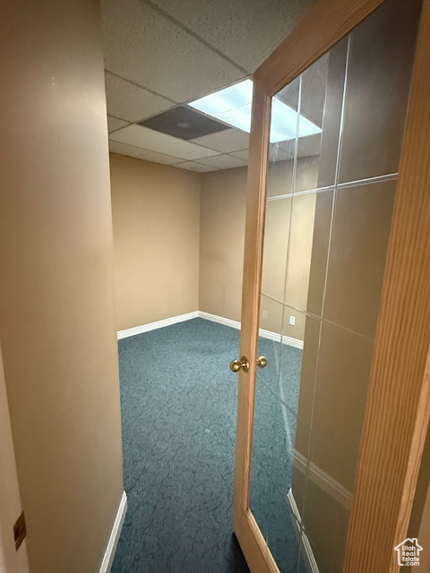 Finished basement featuring carpet flooring, baseboards, and a paneled ceiling