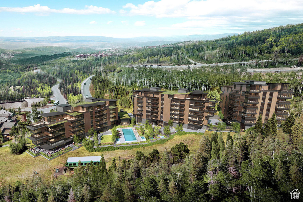 Aerial view of property and surrounding area featuring a heavily wooded area and a mountainous background