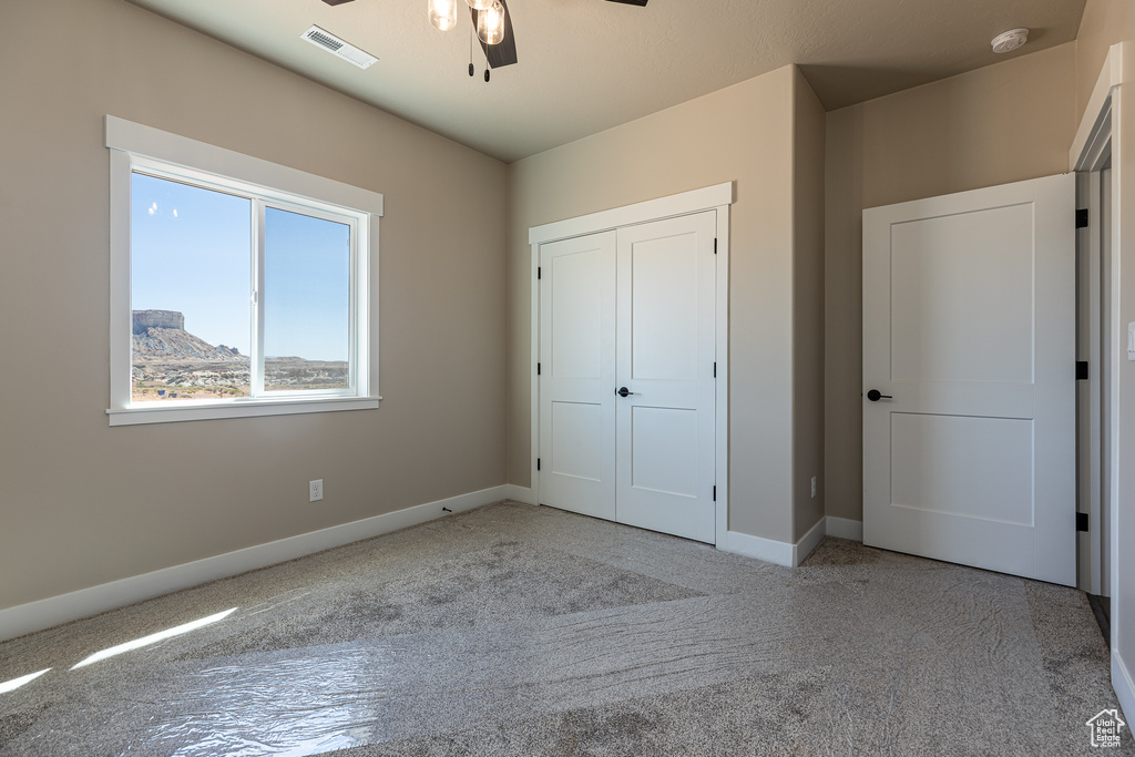 Unfurnished bedroom featuring baseboards, carpet, a closet, and a ceiling fan