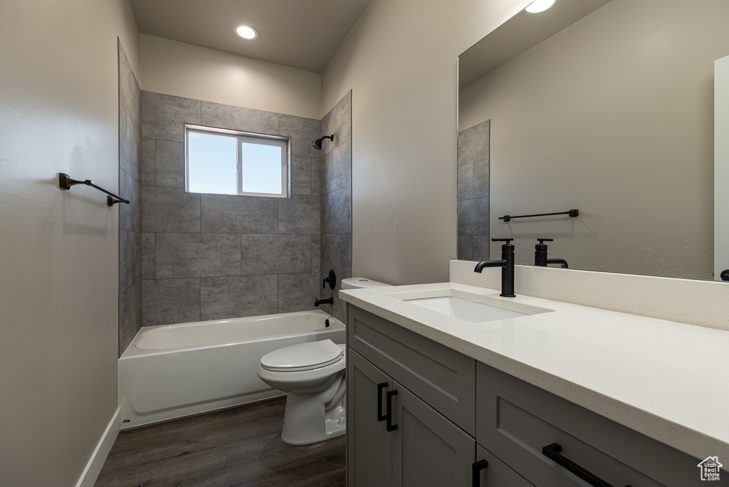 Full bathroom with wood finished floors, toilet, bathtub / shower combination, vanity, and recessed lighting