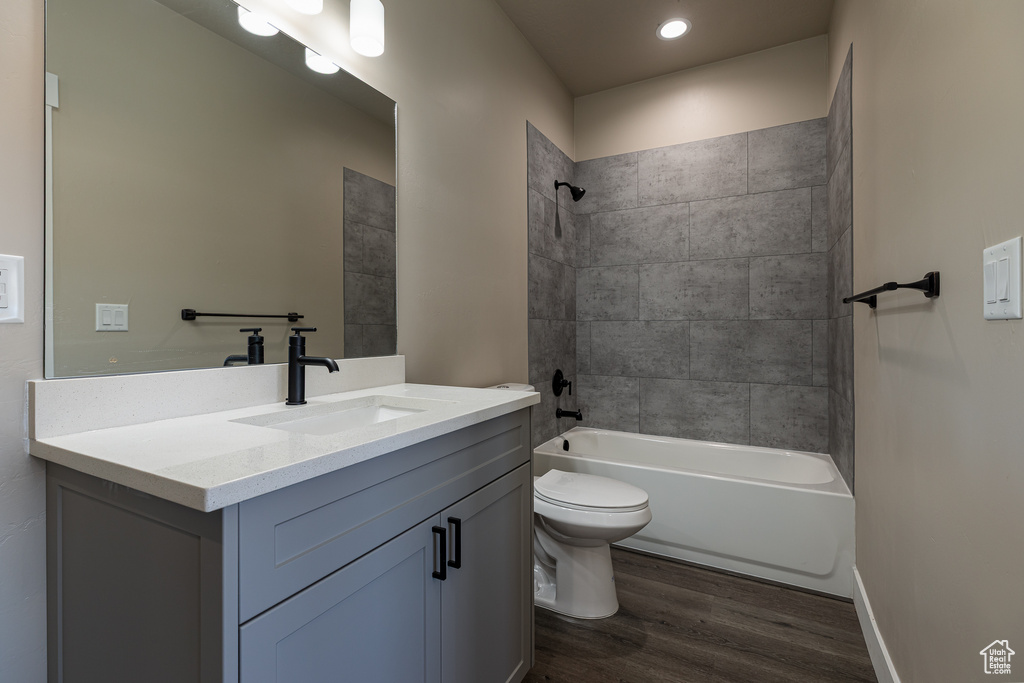 Bathroom with wood finished floors, toilet, vanity, shower / tub combination, and recessed lighting