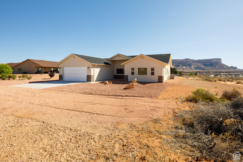 Single story home featuring stucco siding, driveway, a garage, and a mountain view
