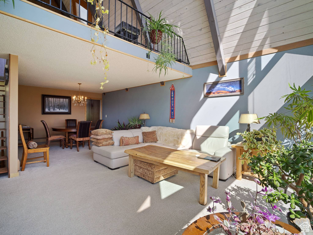 Carpeted living area with a chandelier, beamed ceiling, and high vaulted ceiling