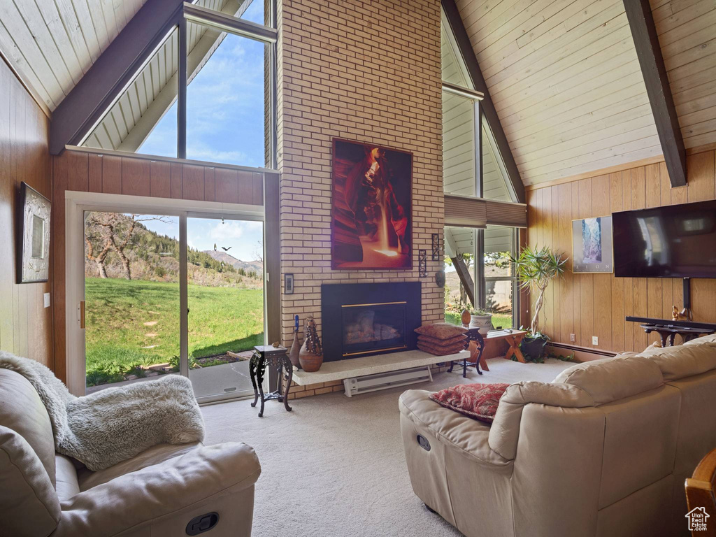 Living area with high vaulted ceiling, wood walls, carpet flooring, a fireplace, and beam ceiling