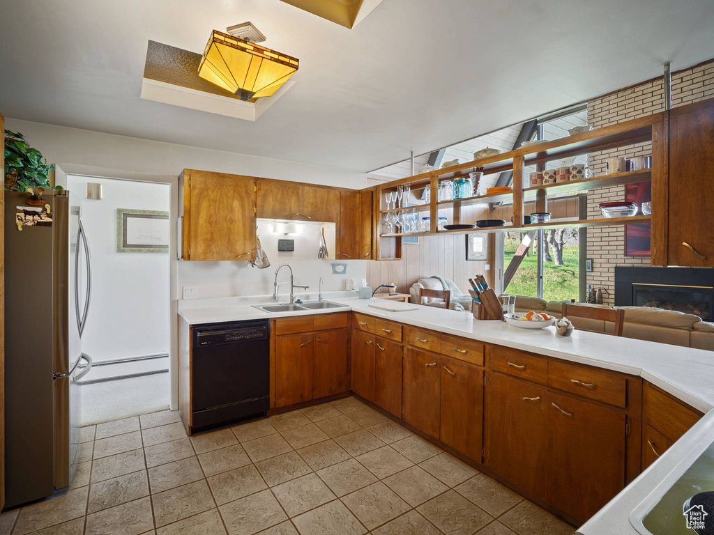 Kitchen with black dishwasher, freestanding refrigerator, a sink, light countertops, and baseboard heating