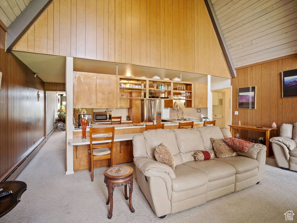 Living area featuring light carpet, wood walls, high vaulted ceiling, a baseboard radiator, and wood ceiling