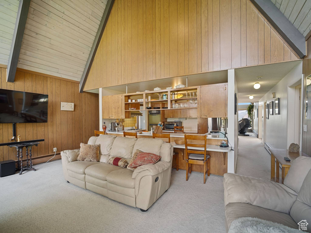 Living area featuring light colored carpet, wood walls, high vaulted ceiling, and beam ceiling