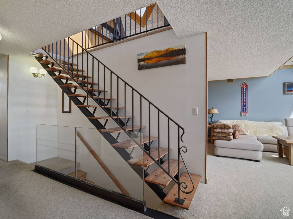 Staircase featuring carpet floors and a textured ceiling