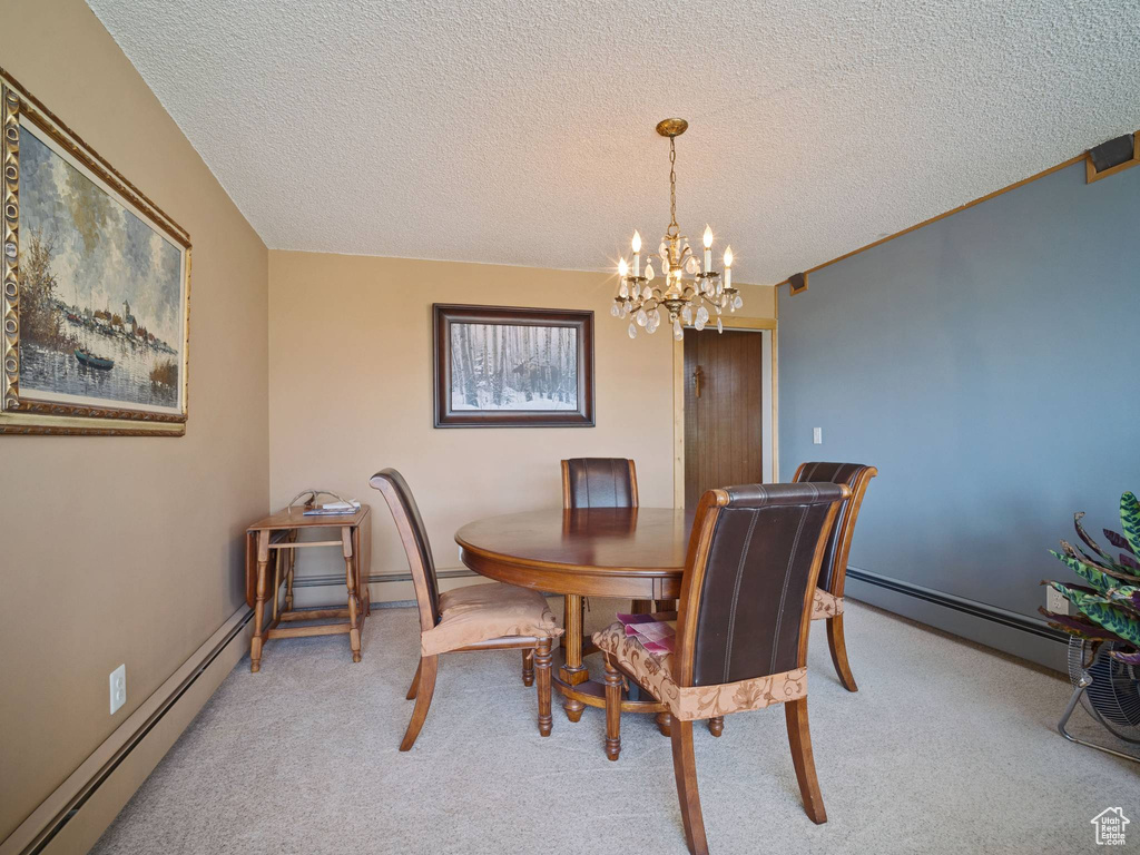 Dining room with a chandelier, a textured ceiling, a baseboard radiator, and light colored carpet