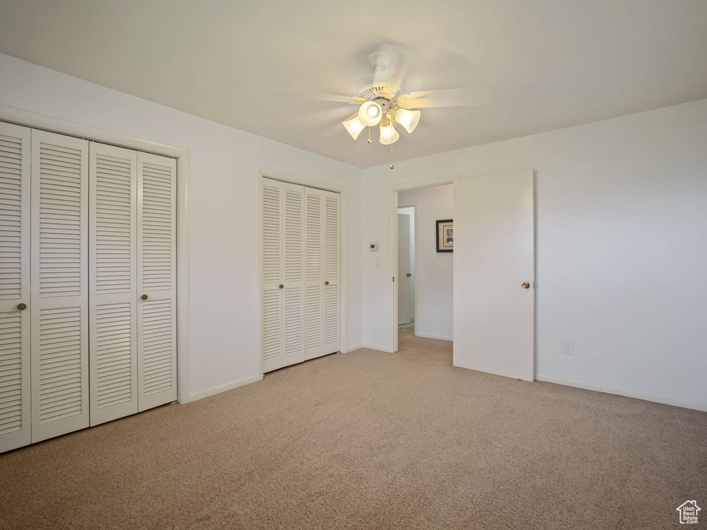 Unfurnished bedroom featuring multiple closets, carpet floors, ceiling fan, and baseboards