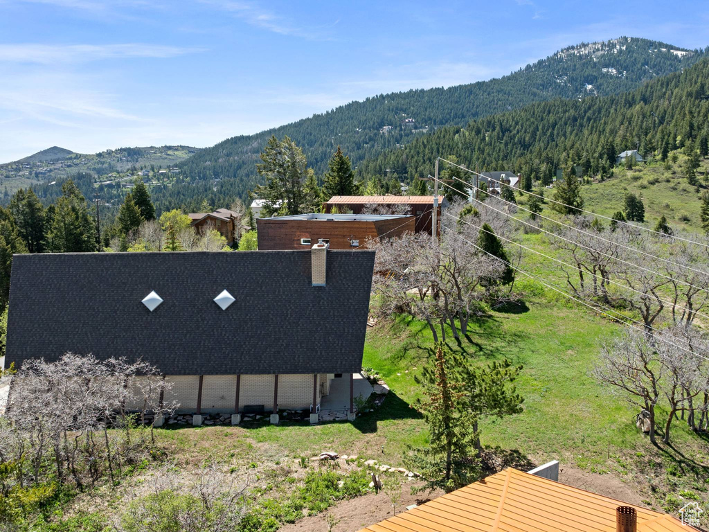 View of subject property featuring a mountain backdrop and a forest