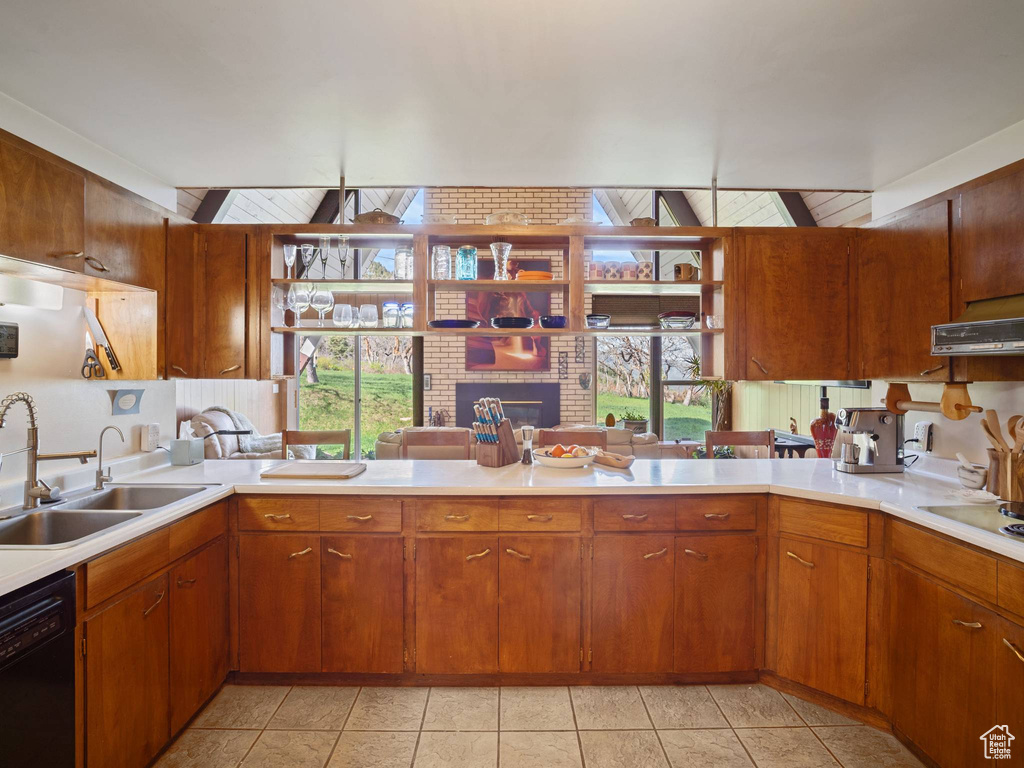 Kitchen featuring black dishwasher, a sink, light countertops, and a brick fireplace