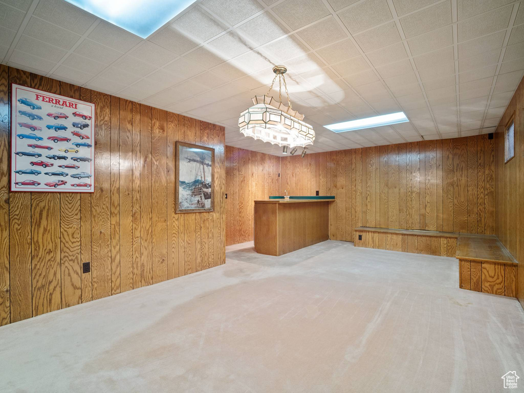 Unfurnished room featuring wooden walls and light carpet