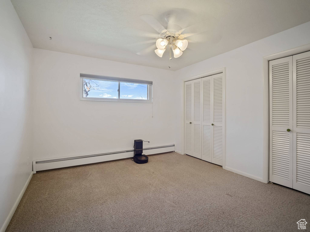 Unfurnished bedroom featuring two closets, carpet flooring, and baseboards