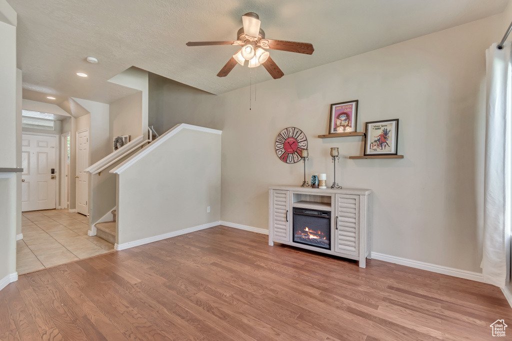 Unfurnished living room with wood finished floors, ceiling fan, baseboards, recessed lighting, and a glass covered fireplace