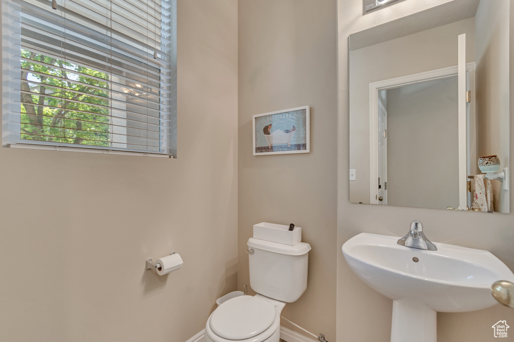 Half bathroom with a sink, toilet, and baseboards