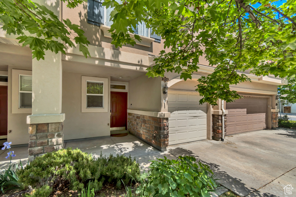View of front of home with stone siding, driveway, stucco siding, and an attached garage