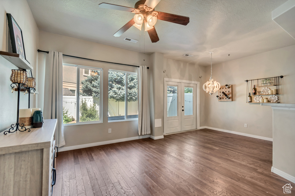 Doorway to outside featuring dark wood-type flooring, baseboards, a chandelier, a ceiling fan, and a textured ceiling