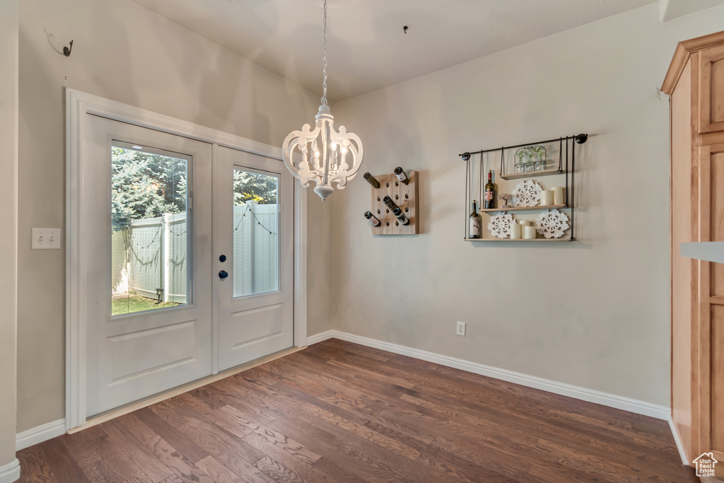 Doorway to outside with dark wood-style floors, a chandelier, and baseboards