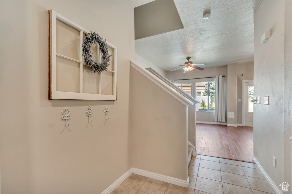 Stairway with ceiling fan, tile patterned flooring, baseboards, and a textured ceiling