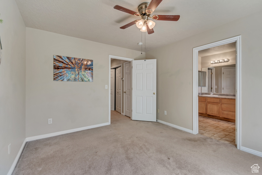 Unfurnished bedroom with light colored carpet, baseboards, a sink, and ensuite bathroom