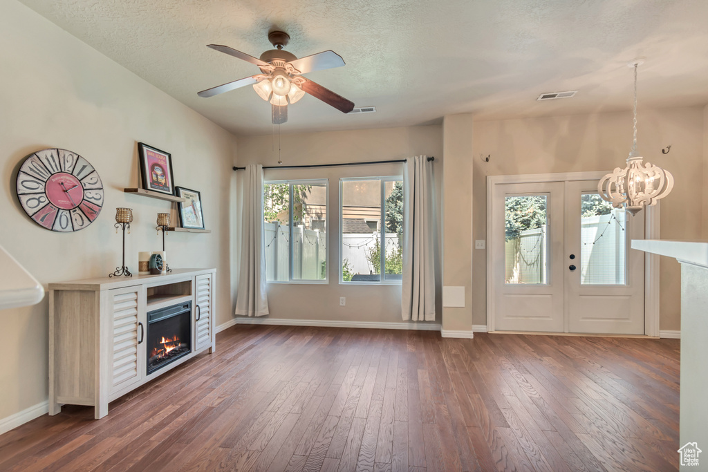 Entryway with wood-type flooring, a lit fireplace, ceiling fan, a chandelier, and a textured ceiling