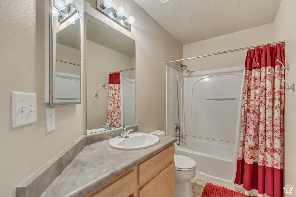Full bathroom with toilet, shower / bath combo, vanity, a textured ceiling, and tile patterned flooring