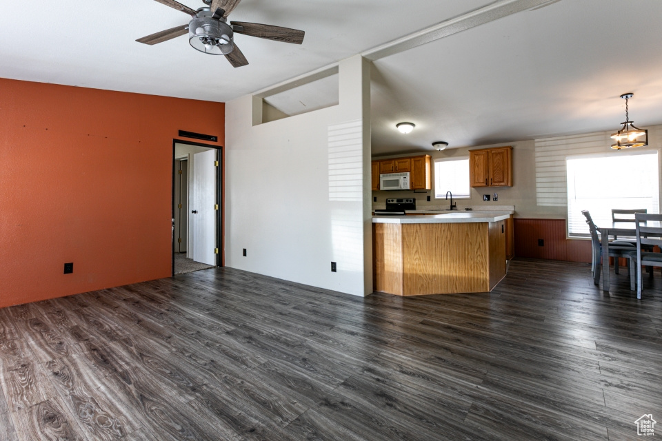 Kitchen with white microwave, electric stove, a sink, light countertops, and ceiling fan