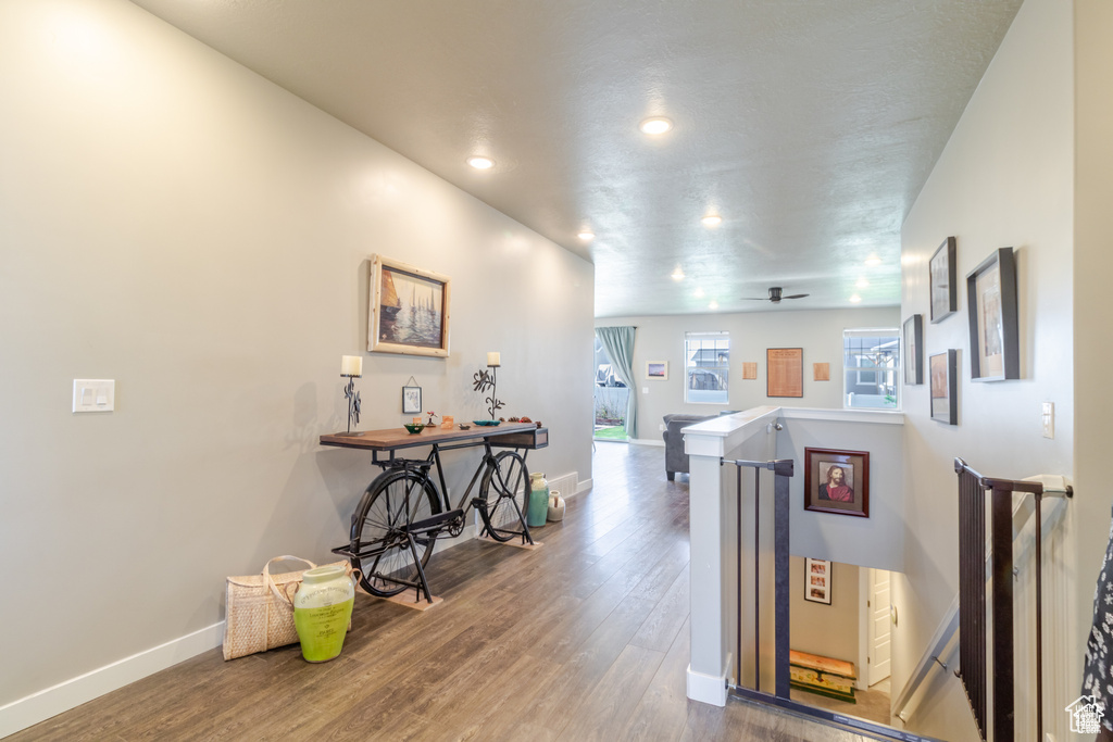 Hallway featuring an upstairs landing, wood finished floors, baseboards, and recessed lighting