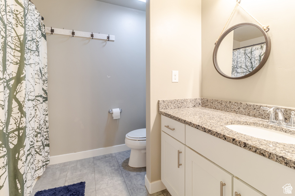 Bathroom with toilet, vanity, baseboards, and tile patterned floors