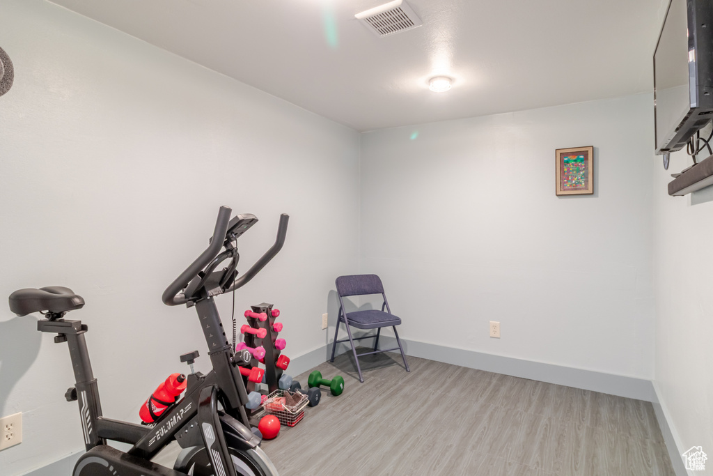 Exercise area with light wood-type flooring and baseboards