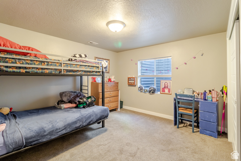 Carpeted bedroom featuring a textured ceiling and baseboards