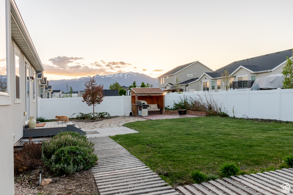 View of yard with a patio, a storage unit, an outbuilding, a deck with mountain view, and a residential view