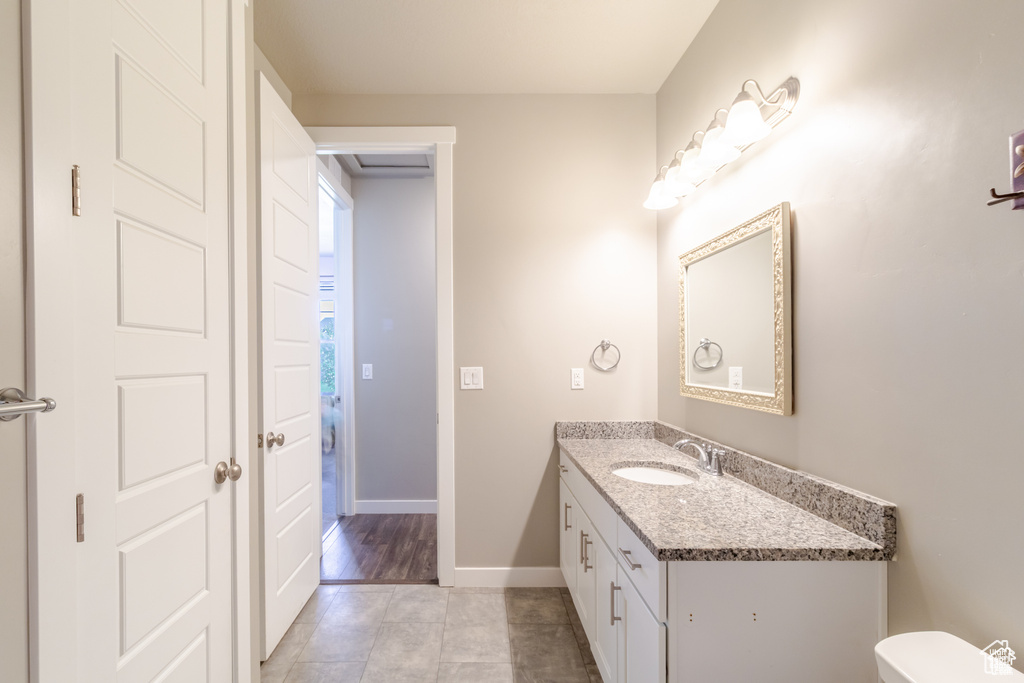 Half bathroom featuring vanity, tile patterned floors, baseboards, and toilet