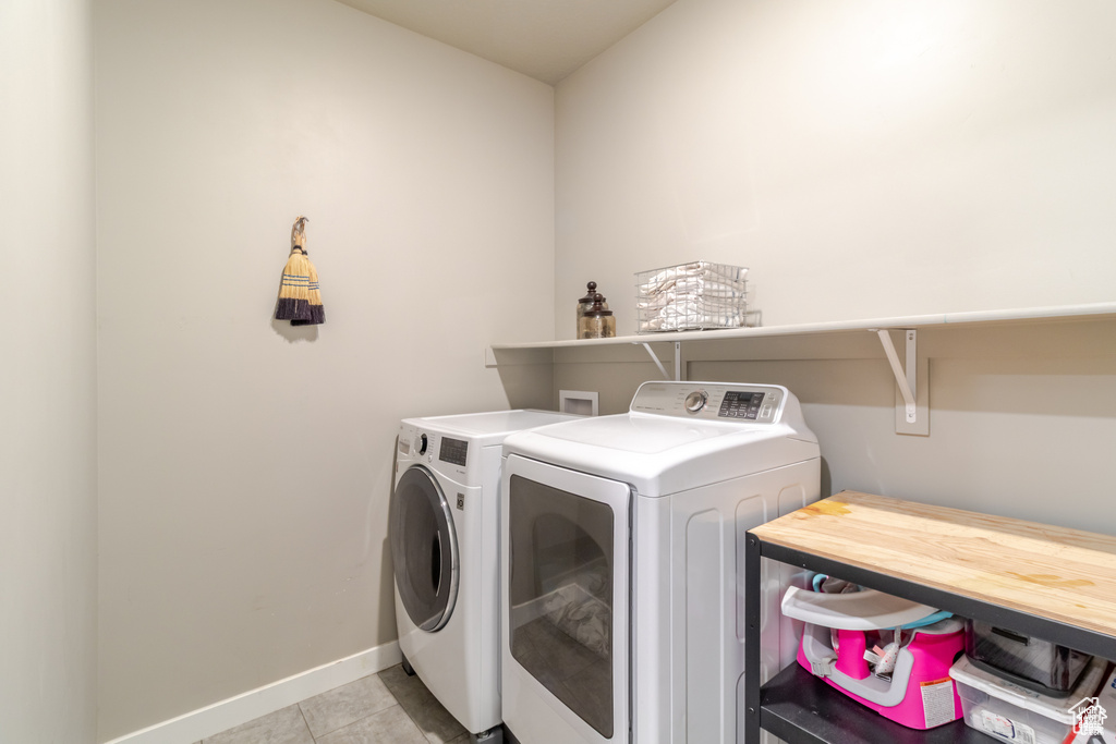 Laundry room with washer and dryer, baseboards, and light tile patterned floors