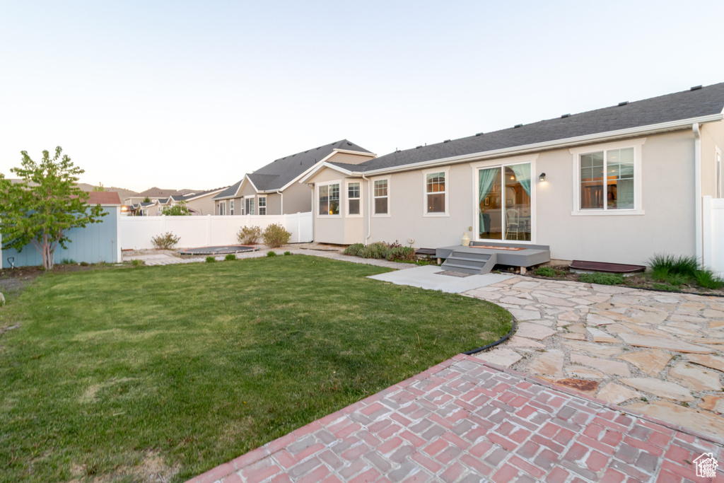 Rear view of property featuring stucco siding, a patio, an outbuilding, and a storage shed