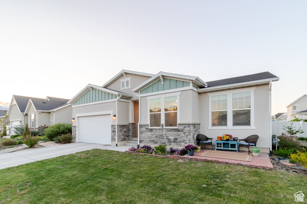 View of front of house featuring concrete driveway, board and batten siding, an attached garage, stone siding, and stucco siding