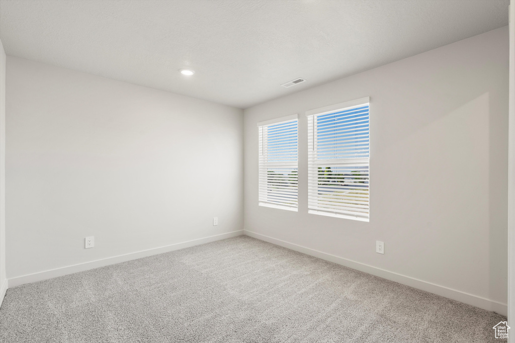 Empty room with light carpet and recessed lighting